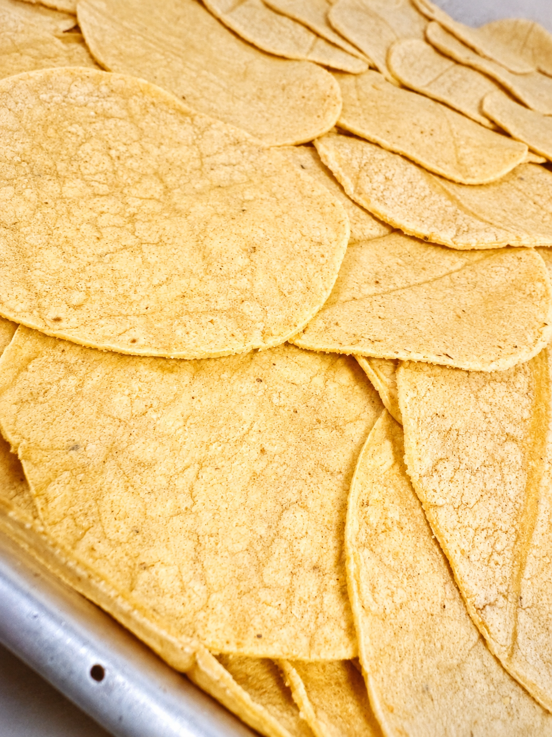 Fresh, warm corn tortillas stacked in a metal tray